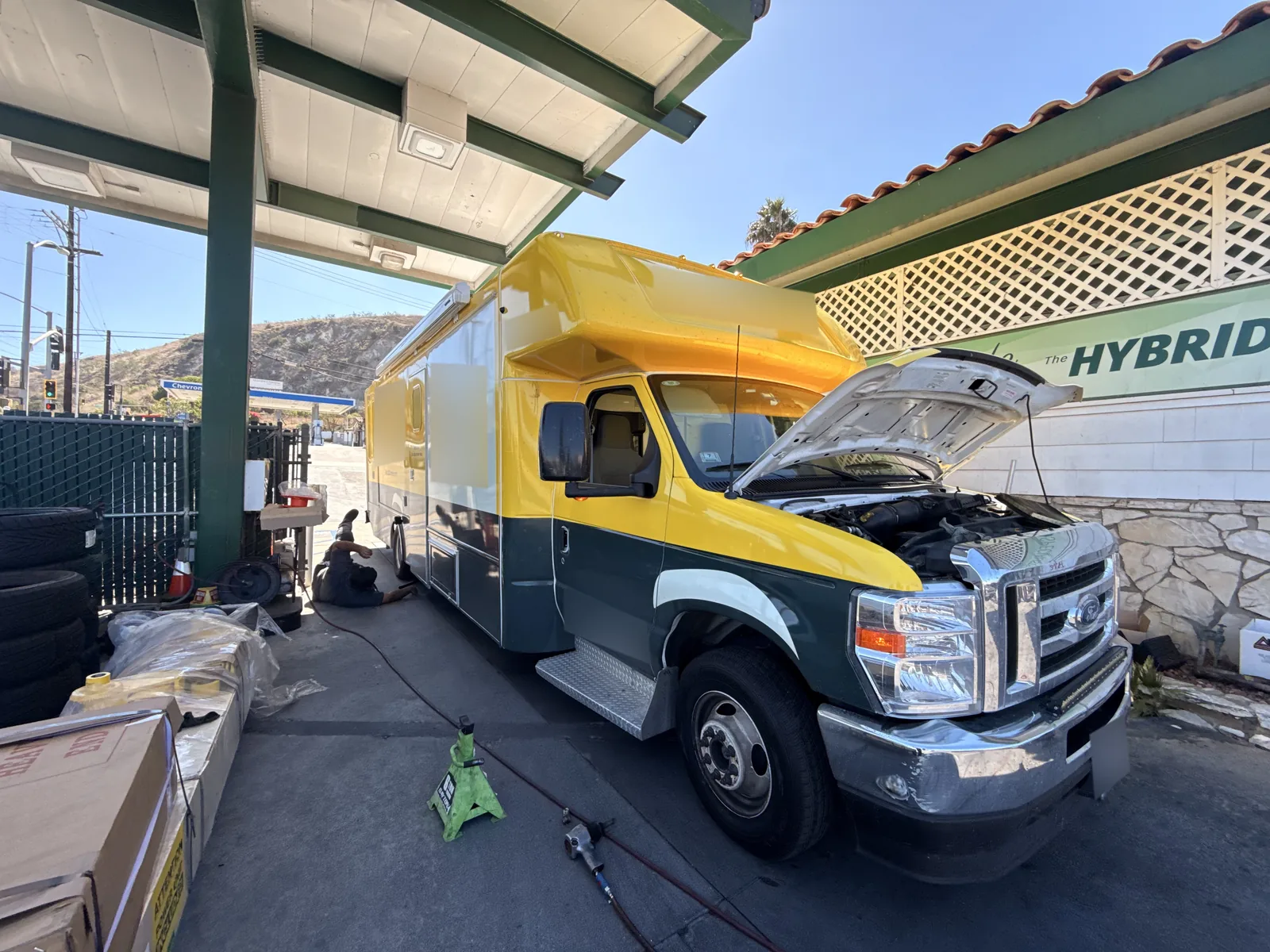 Small yellow-and-green commercial bus at Hillside with its hood open.