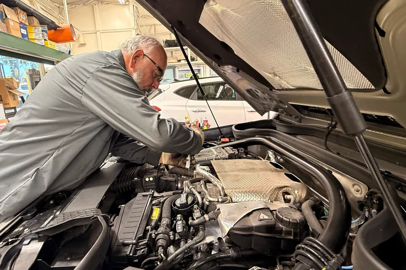 Hillside technician working under the hood of a vehicle in the shop