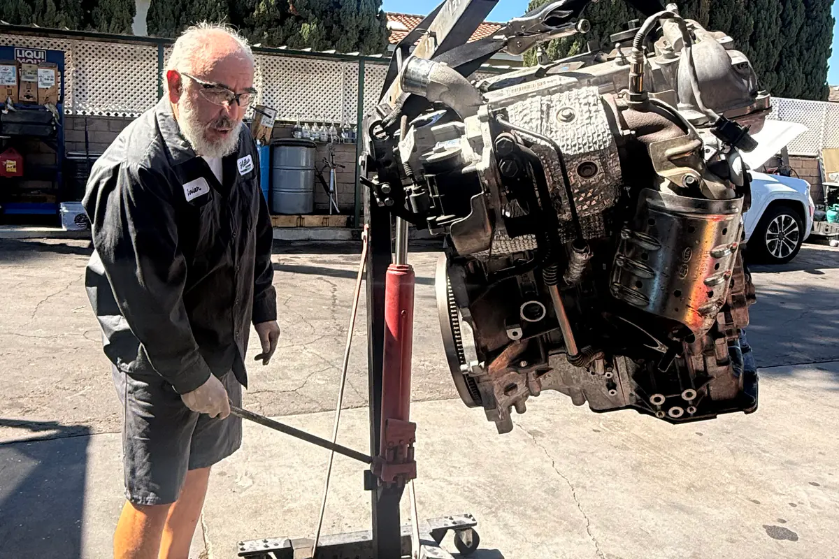 Hillside technician beside an engine on a hoist